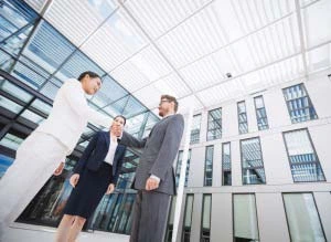 Drei Geschäftsleute vor einem modernen Bürogebäude – Kaufmännisches Gebäudemanagement in Stuttgart für transparente Verwaltung und Kostenkontrolle.